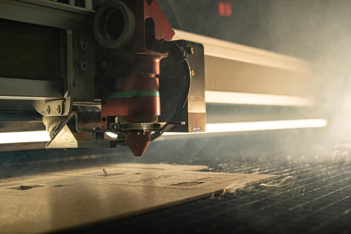 Laserkopf schneidet Holzplatte mit eingraviertem cutcraft-Schriftzug